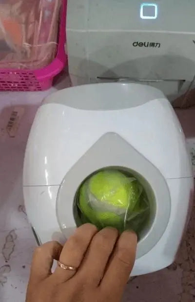 Purrfect Pet Kingdom automatic fetch machine for dogs with tennis ball inside and hand placing ball