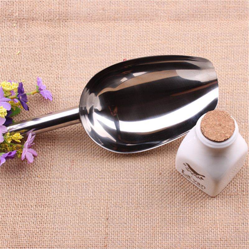 Durable scoops for cat and dog food made of shiny stainless steel with a long handle on burlap background
