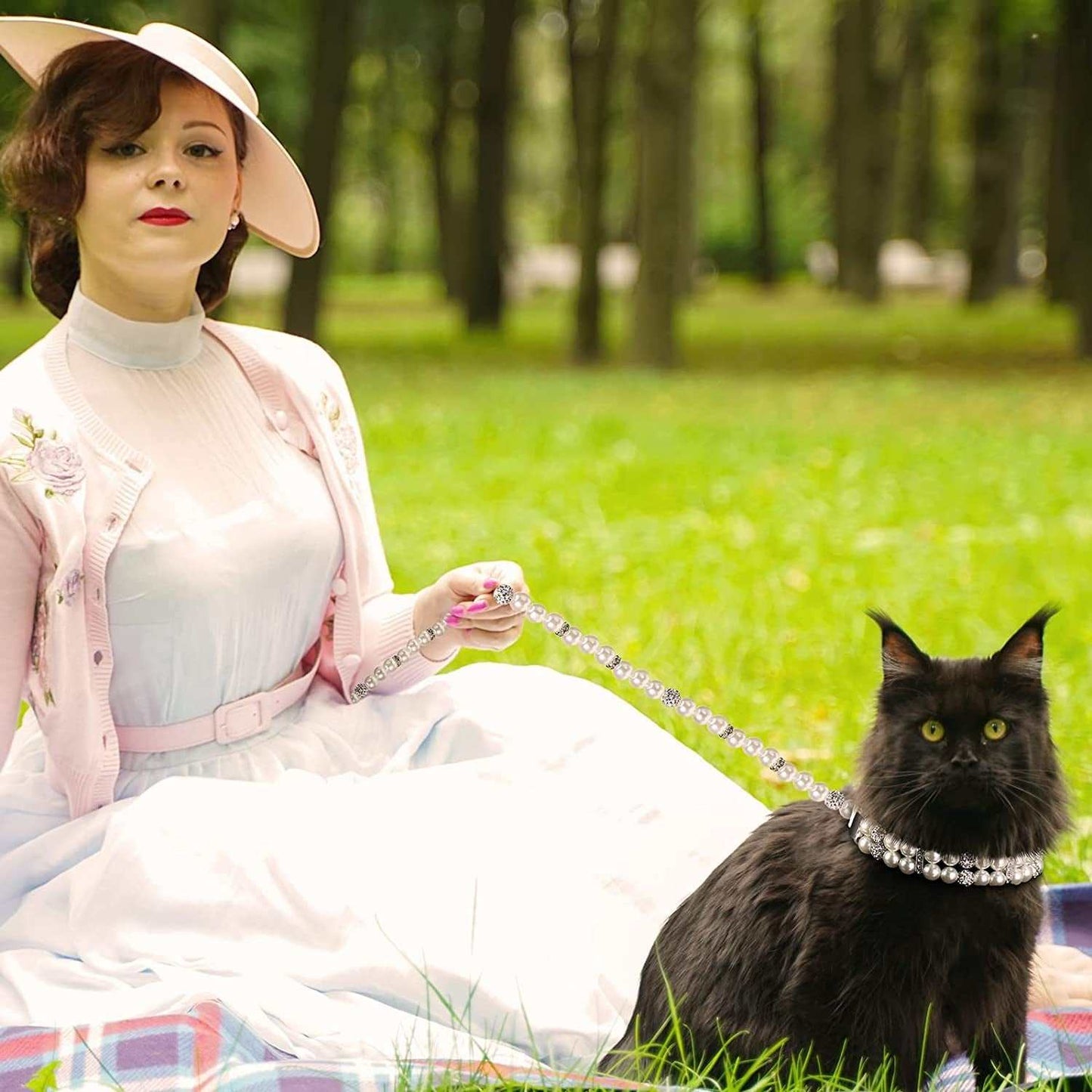 Woman in a pink outfit holding an elegant dog leash with pearls attached to a stylish black cat