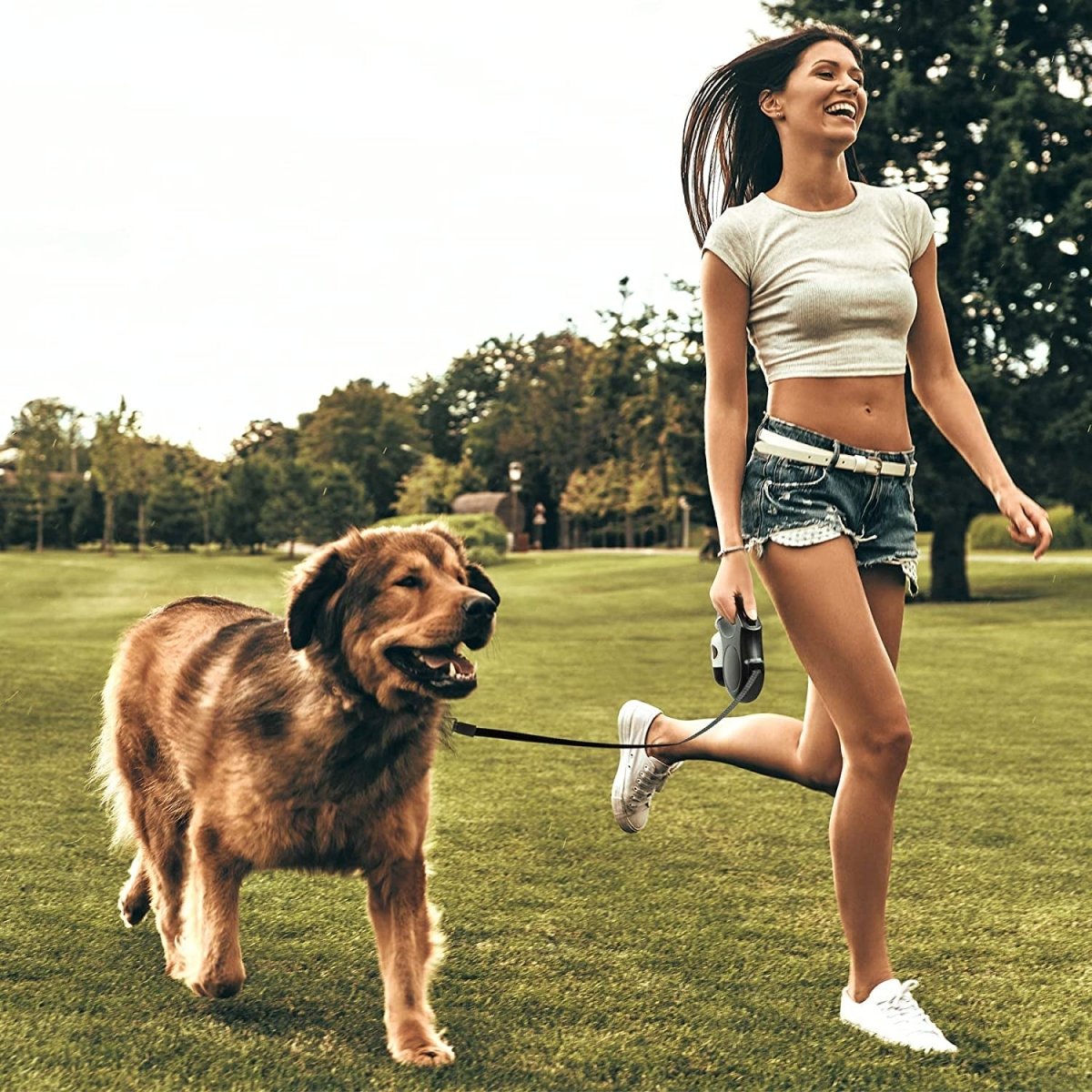 Woman walking a dog in the park using a retractable dog leash for easy control and comfort