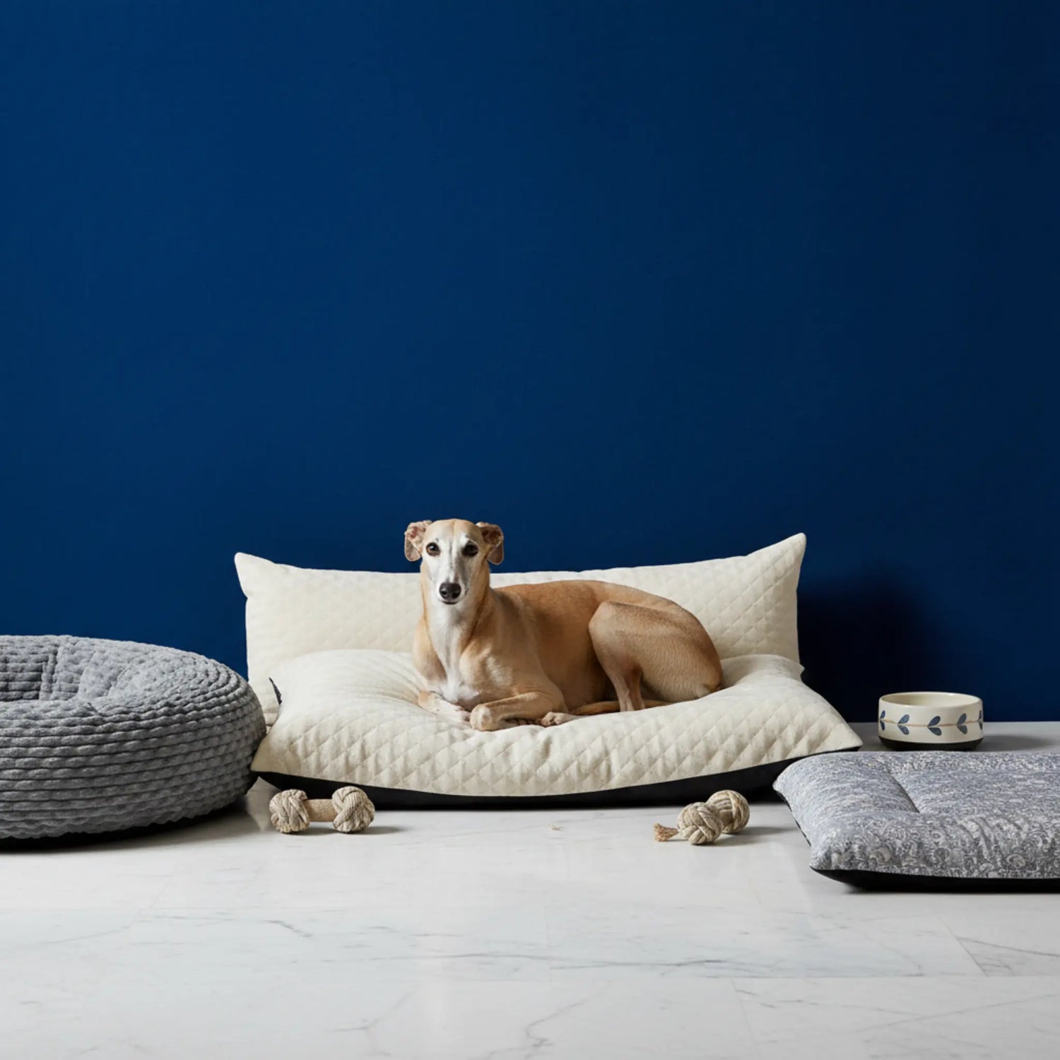 A golden retriever sleeping peacefully on a fluffy, cream-colored plush pillow bed in a sunlit living room.