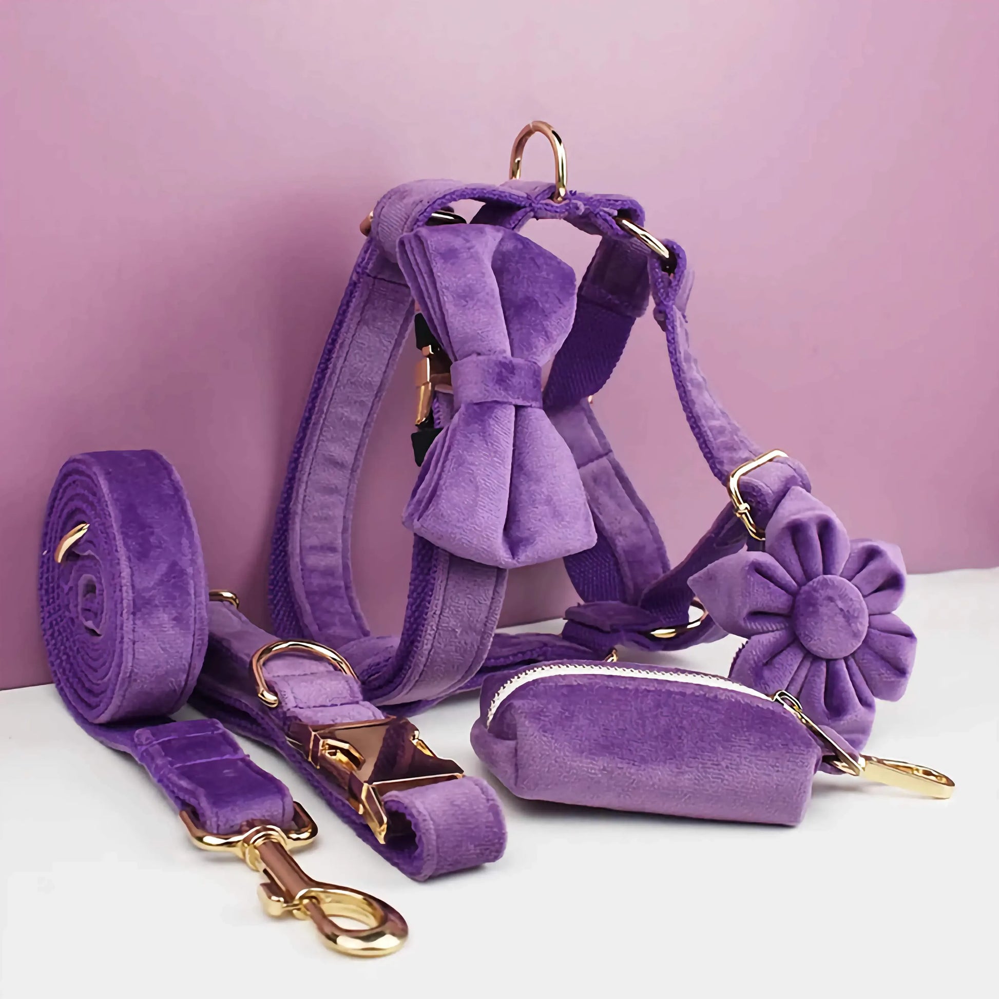 Purrfect Pet Kingdom purple velvet dog harness, collar, leash, and pouch set with gold hardware, bow, and flower.