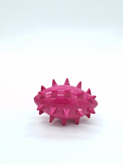 Bright pink football-shaped rubber dog toy with textured spikes. Spikez the Ball by Toys N Treats Box.