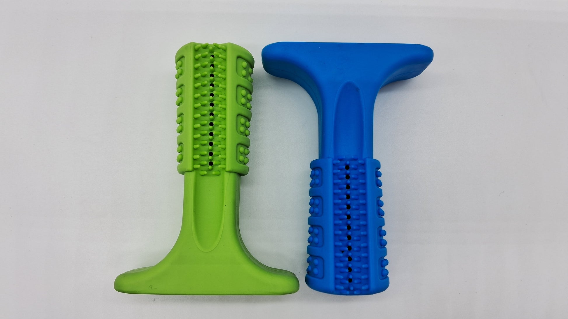Toys N Treats Box The Grinder: Green and blue rubber T-shaped dog toys with textured nubs for dental cleaning.