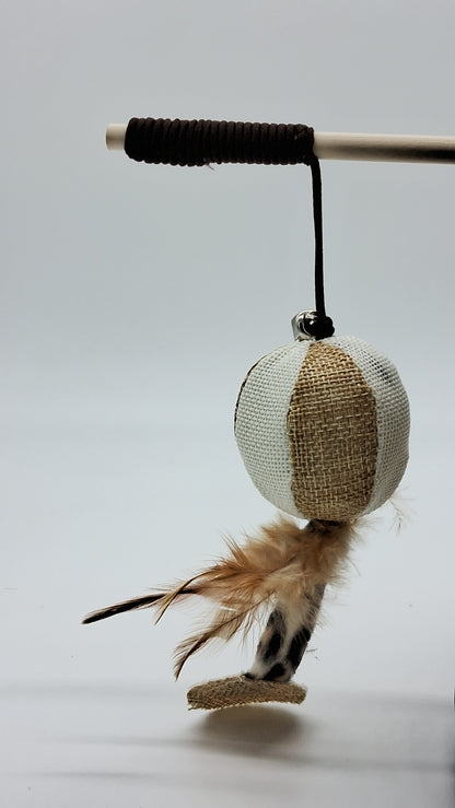 Teaser wand with wooden handle, burlap ball, bell, brown feathers, and leopard print tail from Toys N Treats Box.
