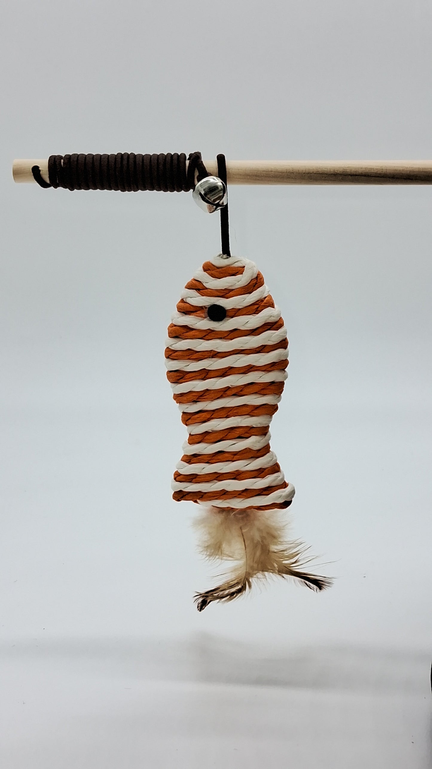 Toys N Treats Box cat teaser wand with wooden rod, bell, and orange and white woven rope fish with feather tail.