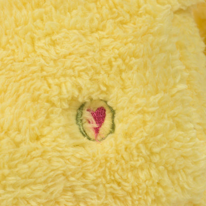 Close-up of yellow sherpa plush material on a Mutt dog toy with an embroidered pink heart in a green circle.