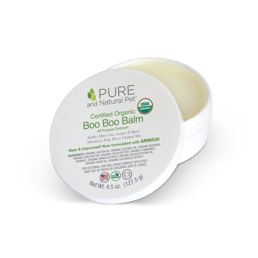 White jar of organic Boo Boo Balm for dogs, propped lid showing green text and USDA Organic seal.