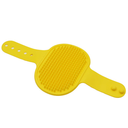 Yellow silicone pet bath brush with soft bristles and an adjustable strap for gentle grooming and deshedding.