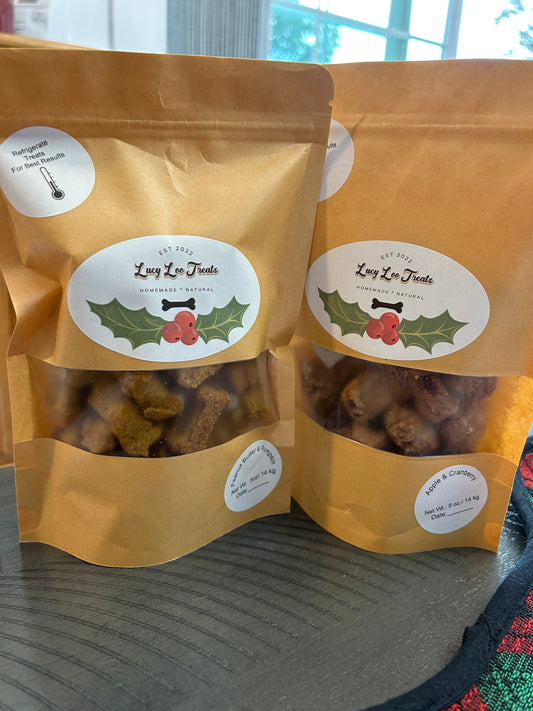 Two brown kraft pouches of Lucy Loo dog treats with clear windows showing bone-shaped snacks and festive labels.