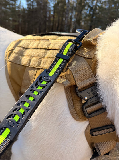 Black and neon yellow reflective leash with built-in traffic handle attached to a tan tactical dog harness.