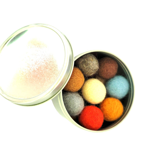 Multi-colored ReNewedPet organic felted wool cat ball toys in a round silver metal tin with a clear lid.