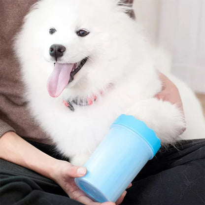 White dog having its paw cleaned in a light blue Purrfect Pet Kingdom silicone portable paw washer cup.