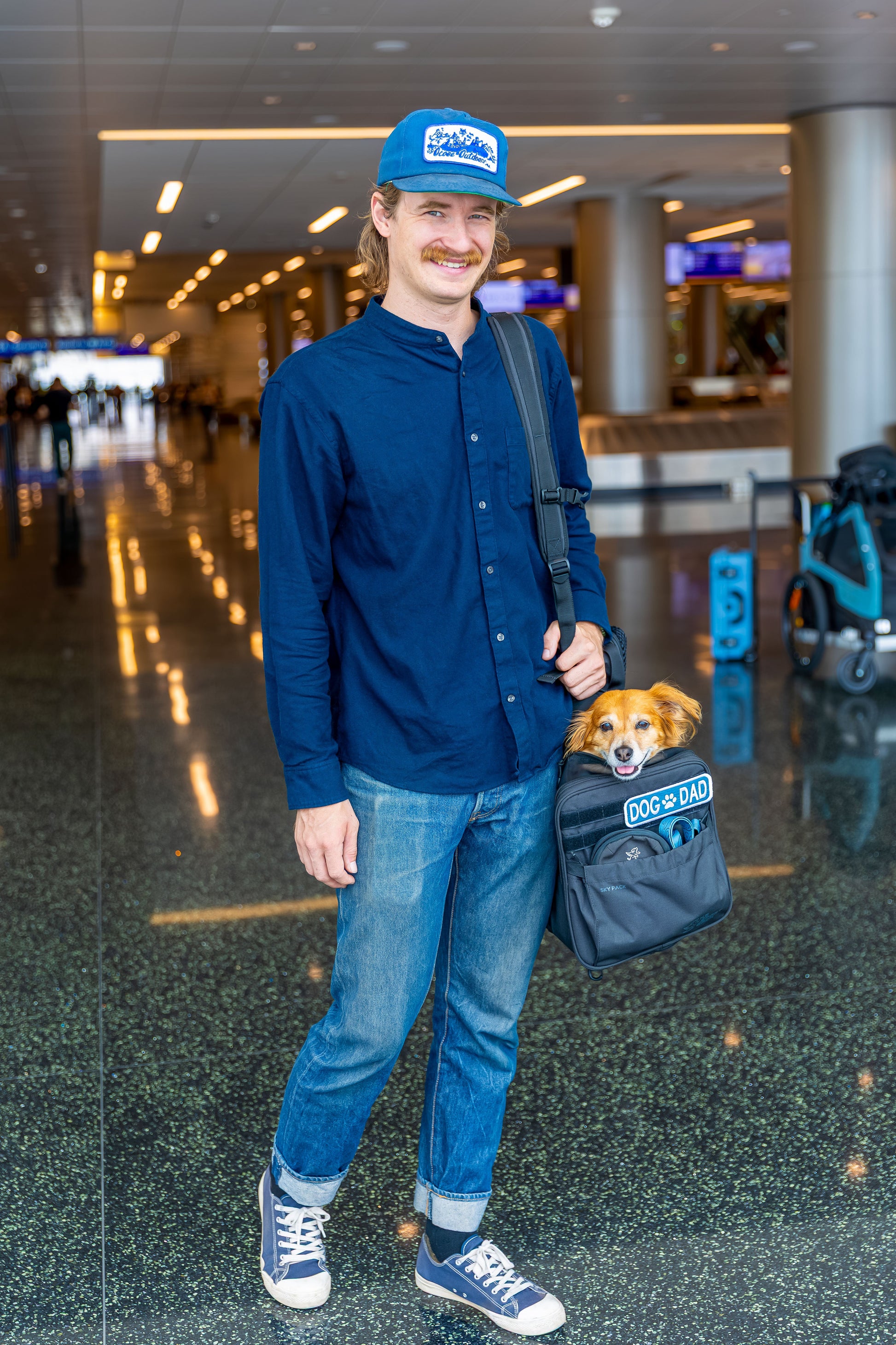 K9 Sport Sack Dog Backpack worn by a man at an airport with a small dog inside