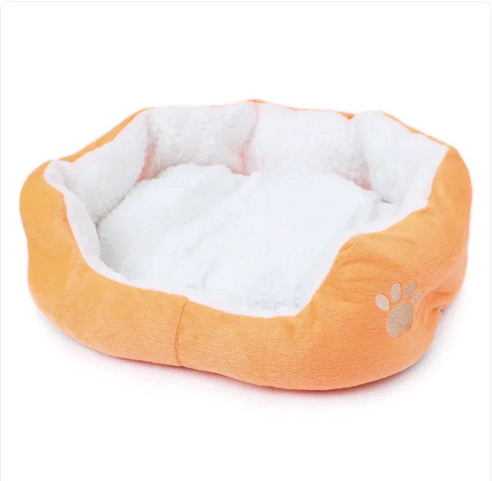 Orange plush pet bed with a white lamb cashmere interior, bolstered sides, and an embroidered tan paw print.