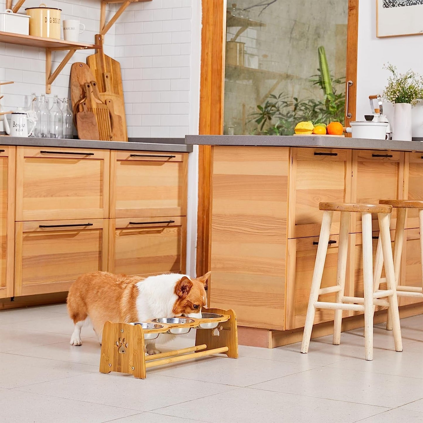 Adjustable bamboo pet feeding station with two stainless steel bowls in a modern kitchen setting