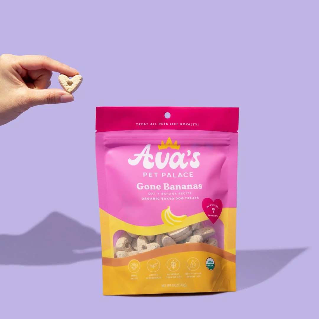 Ava's Pet Dog Treats Gone Bananas organic banana dog treats in a colorful bag with a hand holding a heart-shaped treat
