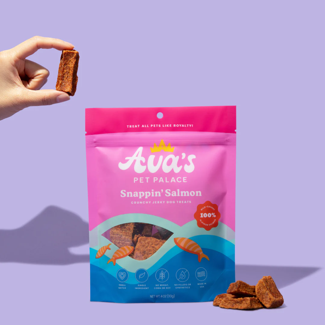 Ava's Pet Palace dog snacks Snapplin' Salmon treats with a hand holding one snack from the package