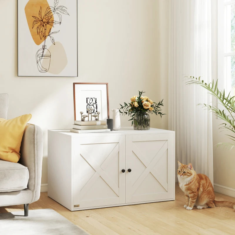 White wooden cat litter box enclosure with barn-style doors and black knobs in a living room next to a ginger cat.