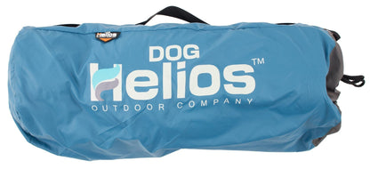 Blue waterproof Helios outdoor dog bed rolled in its carrying bag with a black handle and white logo.