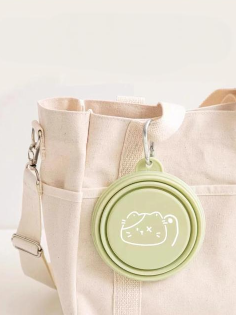 Foldable pet travel bowl in green attached to a canvas bag for easy feeding on the go