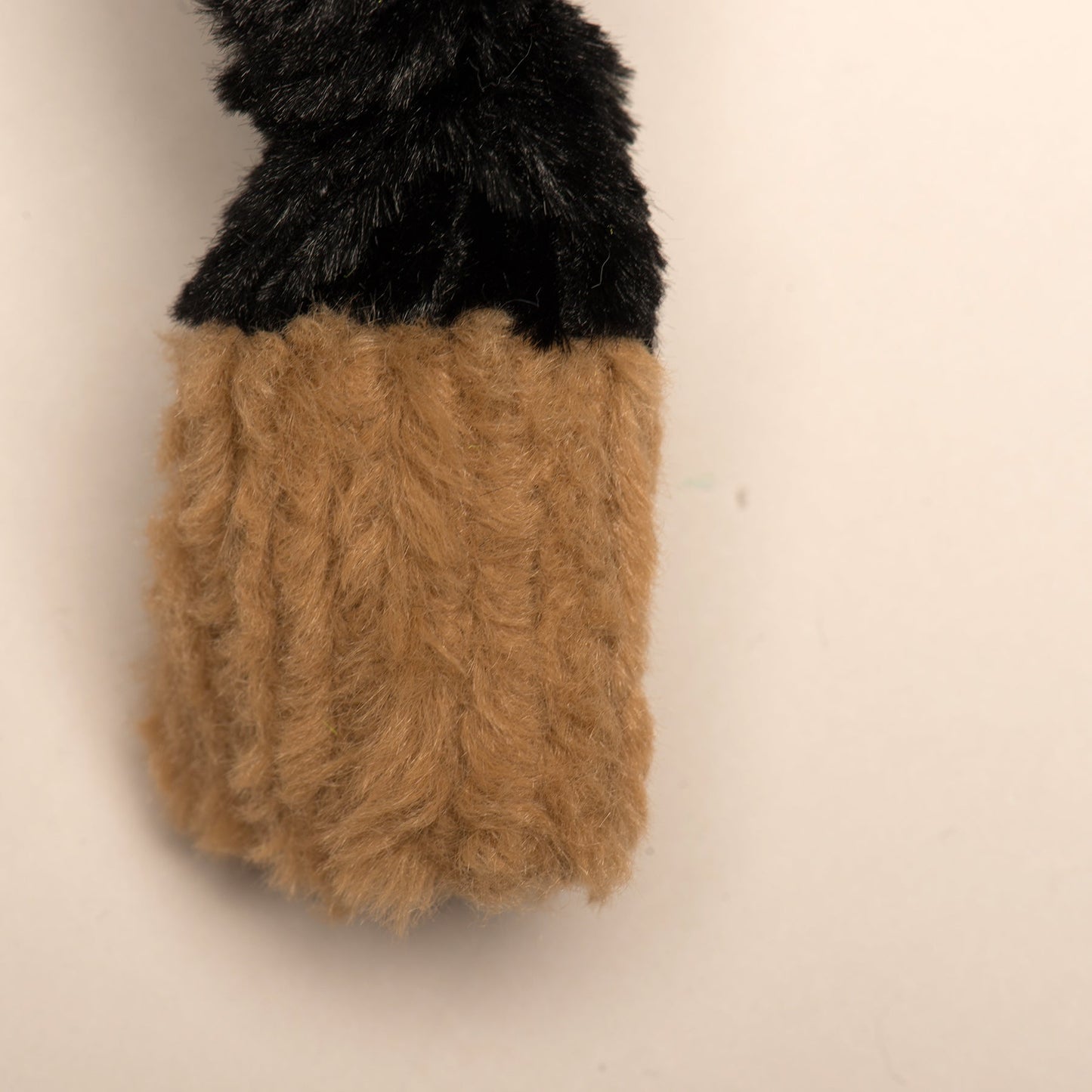 Close-up of black faux fur and tan ribbed plush textures on the Purrfect Pet Kingdom Mattis Hero dog toy.