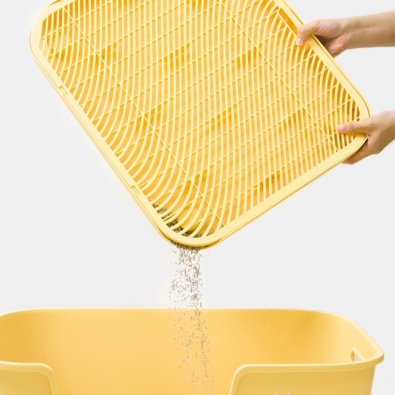 MangoPets best mat for cat litter box featured with a hand pouring litter into a yellow litter box