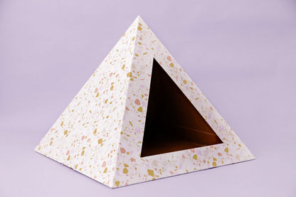 White cardboard pyramid cat nest with pink and gold terrazzo pattern and triangular opening by Purrfect Pet Kingdom.