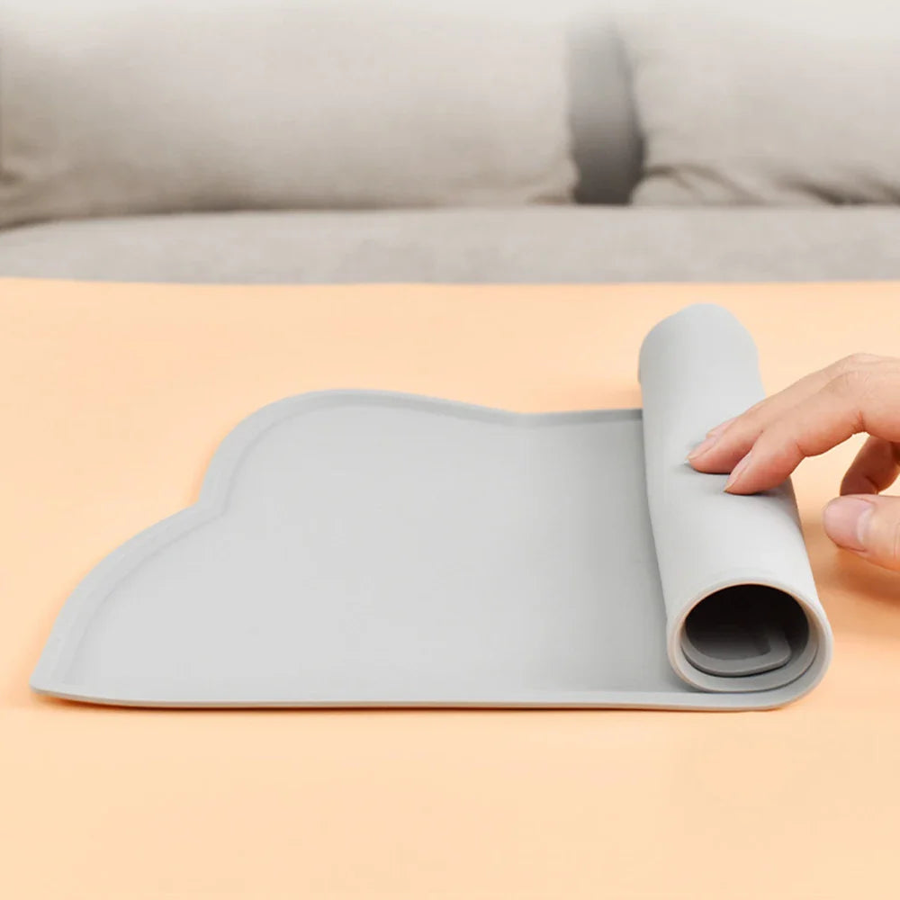 Gray non-slip dog bowl placemat being rolled up for easy storage and cleaning