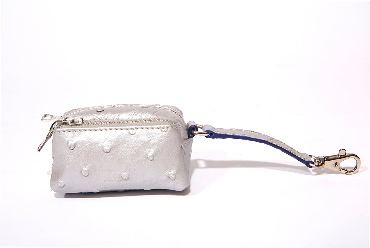 BESPOKE PAWS Silver Ostrich leather dog waste bag dispenser with zipper and blue-accented strap with metal clip.