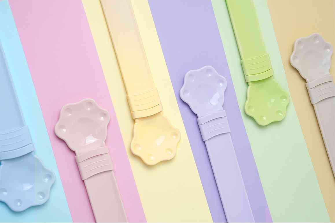 Colorful paw shaped cat treat spoon in pastel shades for serving treats to pets