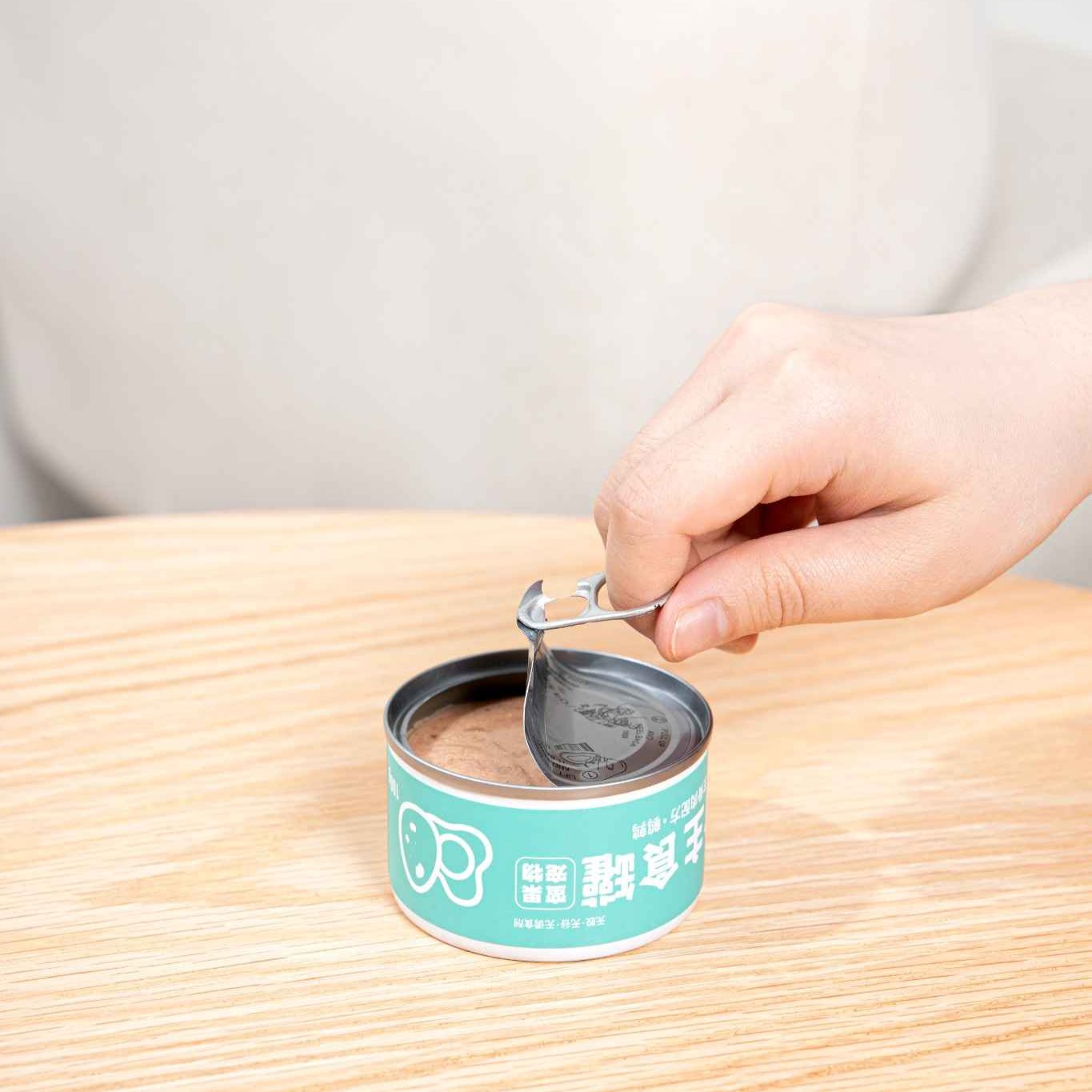 Hand using a pet food can spoon to open a can of MangoPets pet food for easy serving