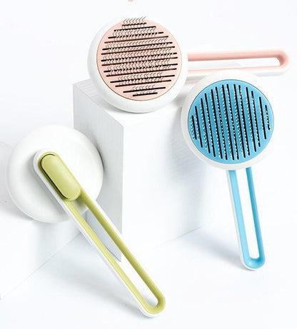 Three Pet Life stainless steel deshedder brushes in pink, blue, and green with round heads and loop handles.