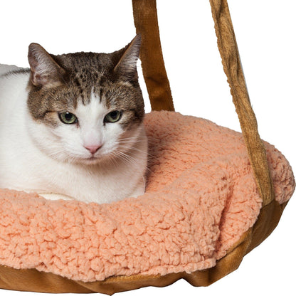 A tabby cat rests in the peach sherpa-lined Pet Life Kittyhaus hanging hammock bed with brown velvet straps.