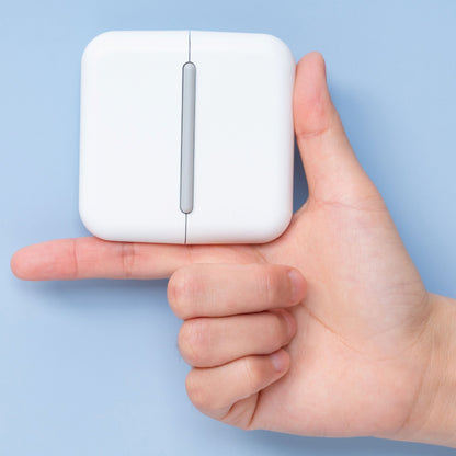 Hand holding a compact white Pet Life travel grooming comb to show its small square size on a blue background.