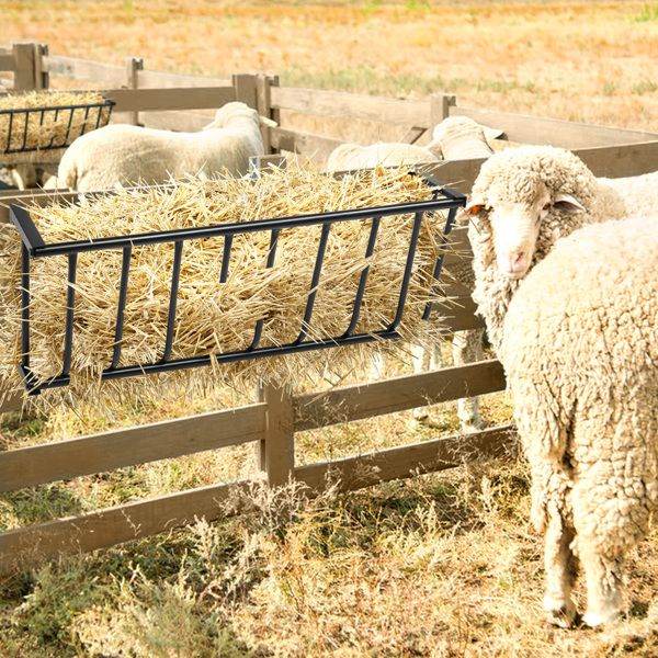 Black metal pet travel car roof rack attached to wooden fence holding hay for sheep