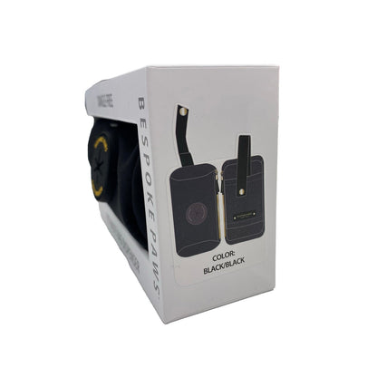 Bespoke Paws black dangle-free leash poop bag dispenser in white box with gold zipper and snap strap.
