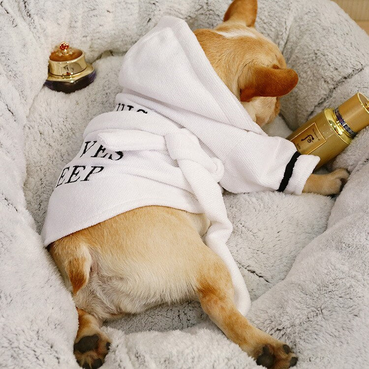 Cozy dog wearing a dog hooded bathrobe, relaxing on a plush pet bed