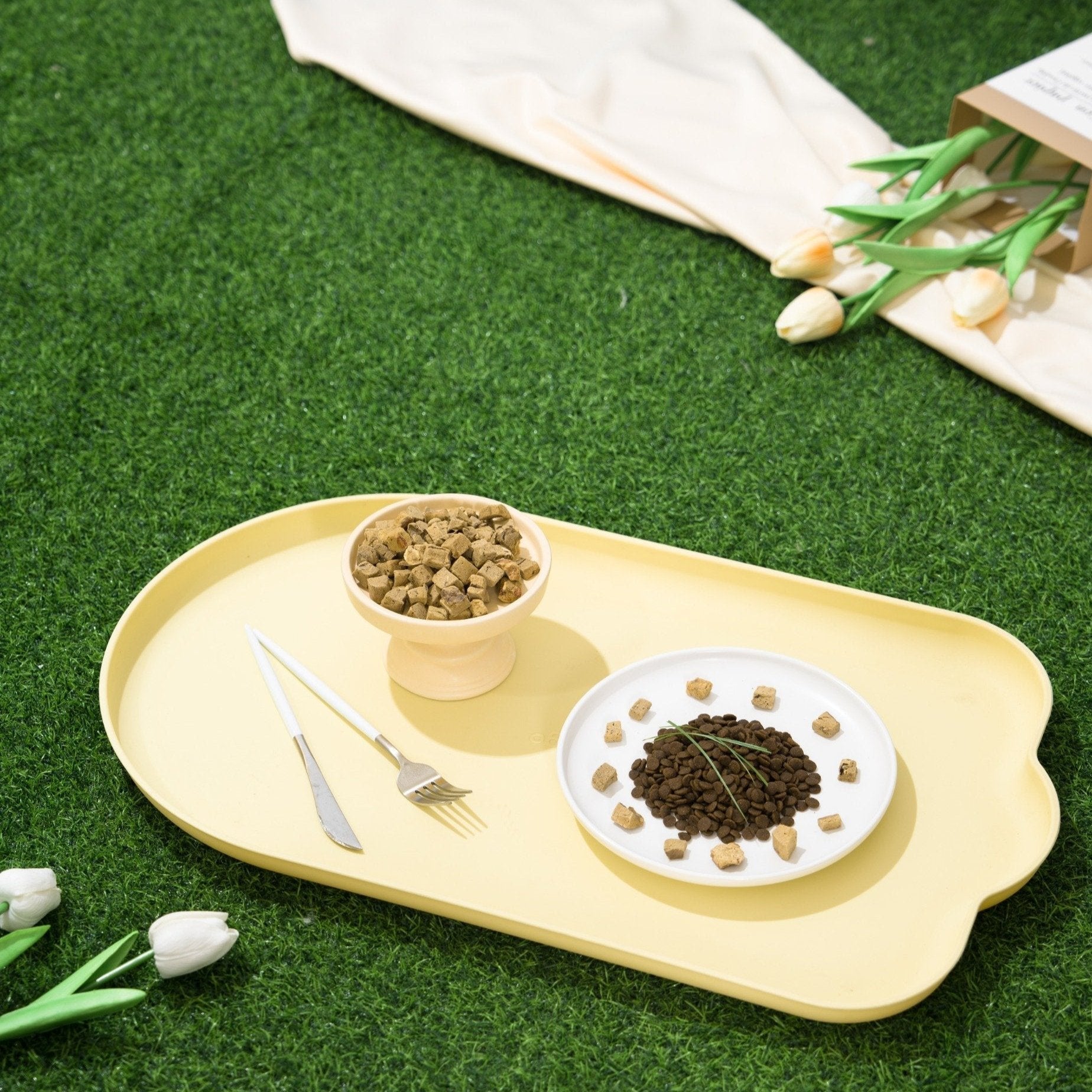 MangoPets waterproof pet feeding mat with bowls showcasing food arrangement on a grassy surface