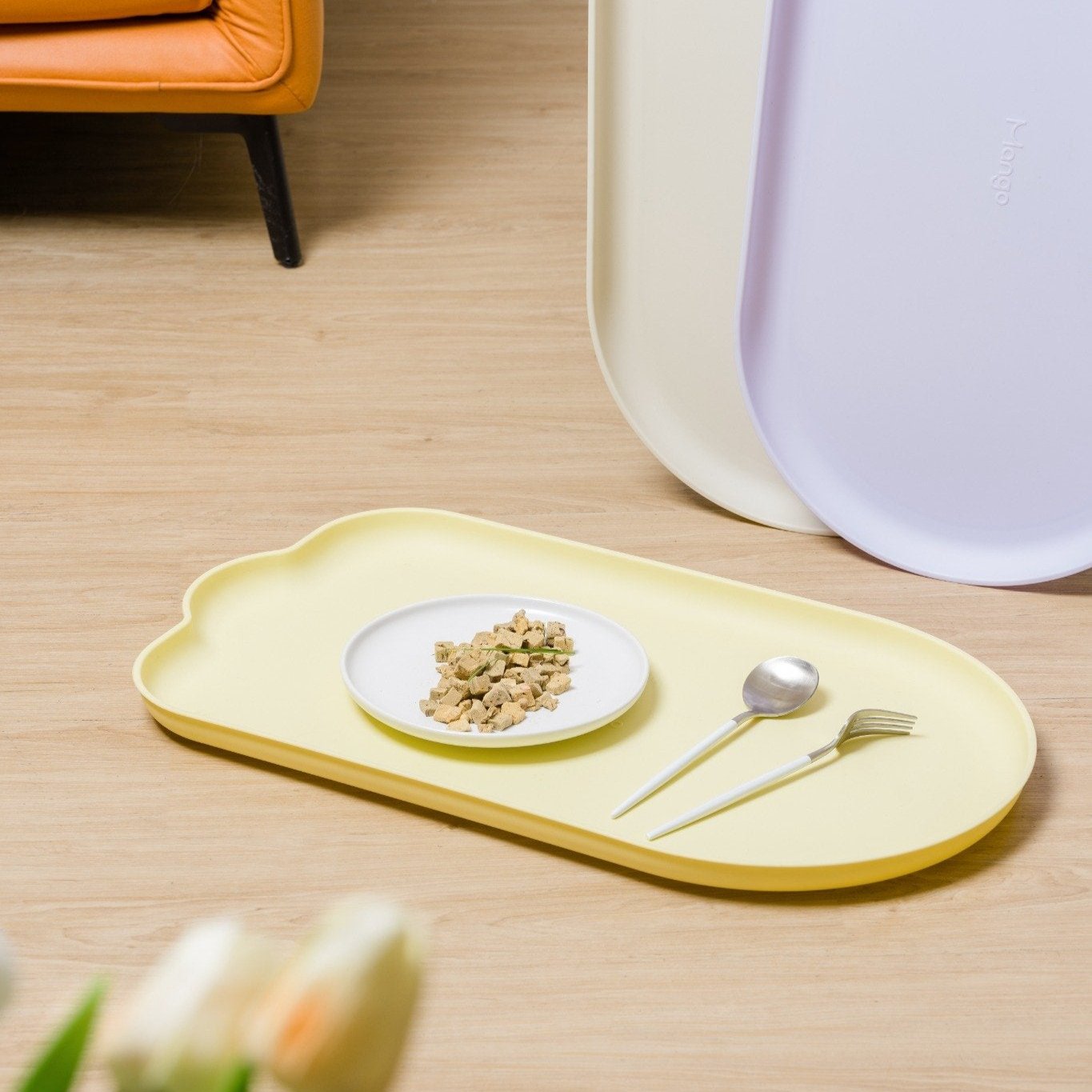 MangoPets waterproof pet feeding mat in yellow with a food bowl and utensils for easy cleanup