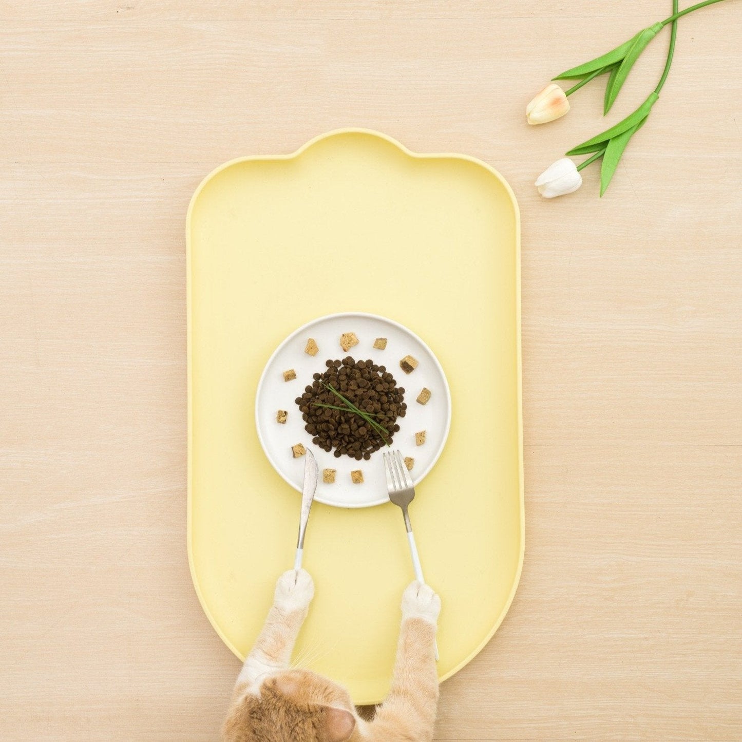 Yellow waterproof pet feeding mat with a bowl of cat food and decorative flowers