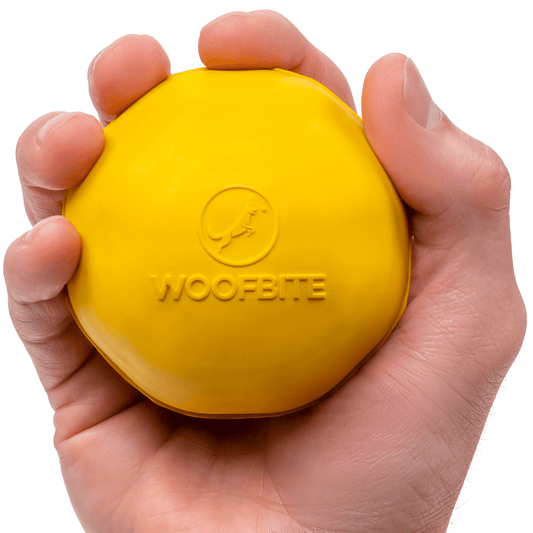 Yellow Monster K9 dog ball toy held in hand, designed for durable playtime with dogs